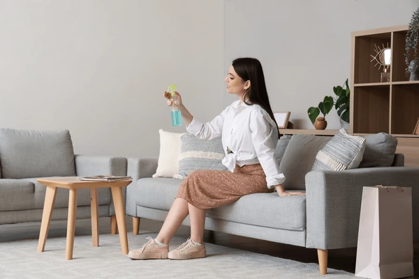 Clean modern living room with a spray bottle of upholstery deodorizer in focus, evoking freshness and cleanliness.